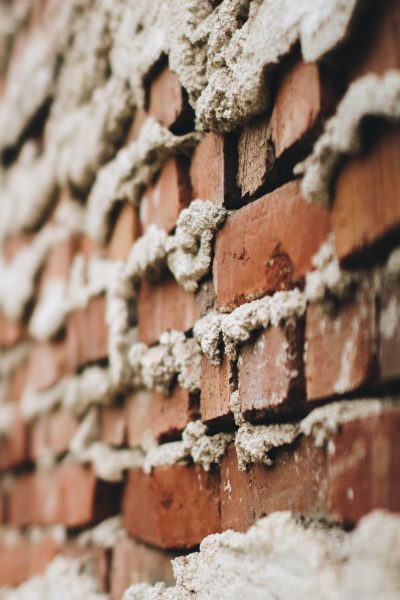 An unevenly built brick wall with cement coming out of the cracks